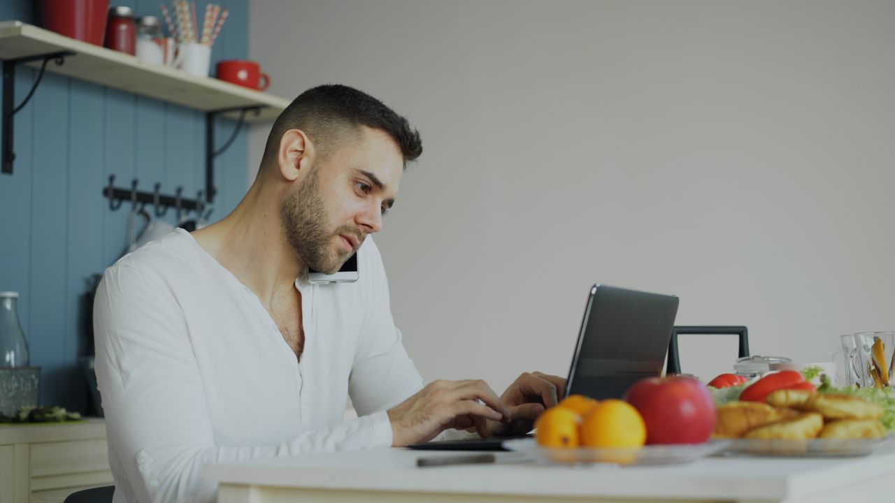 man-working-remotely-in-kitchen-with-laptop-36763311
